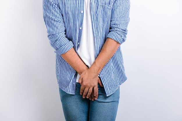 Cropped view of the man holding hands at the genitals while posing at the studio with white background. Urological diseases, pain during urination concept