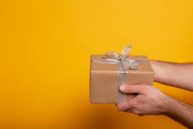 Cropped view of man holding present on yellow