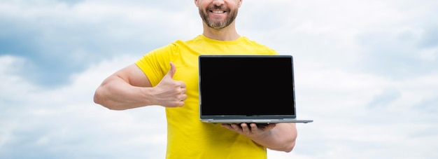 Cropped view of man presenting laptop on sky background copy space