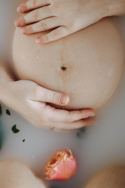 Cropped view of pregnant woman taking bath with flowers and milk