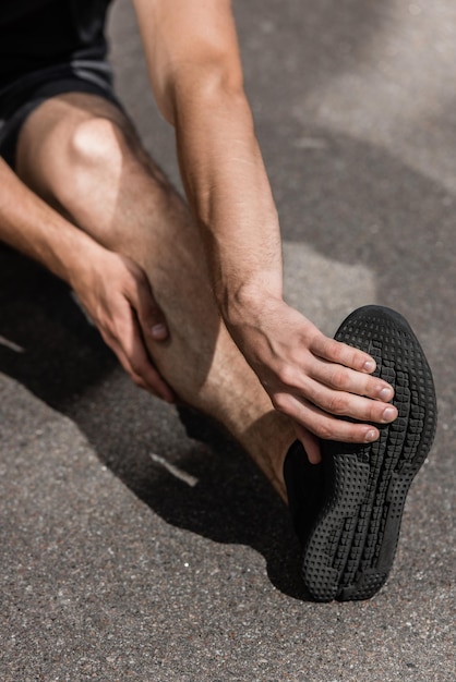 Cropped view of sportsman with leg injury on street