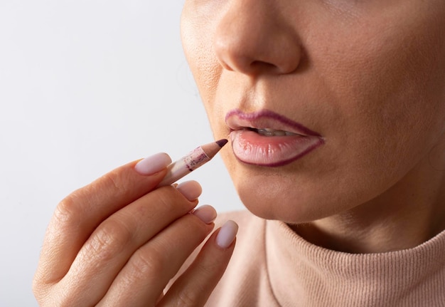 cropped view of woman applying lip pencil