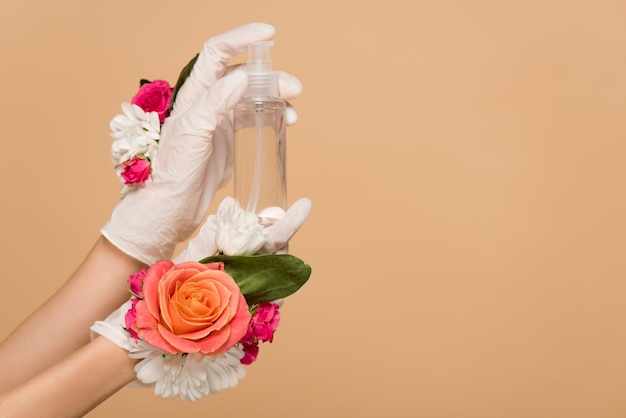 Cropped view of woman in floral latex gloves holding antiseptic spray isolated on beige