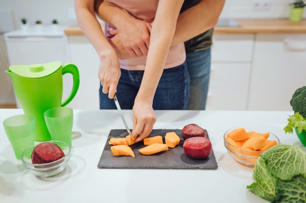 有機野菜を切る女性の手のビューをトリミングしました。ビーガンを愛する家族が台所で野菜を調理します。