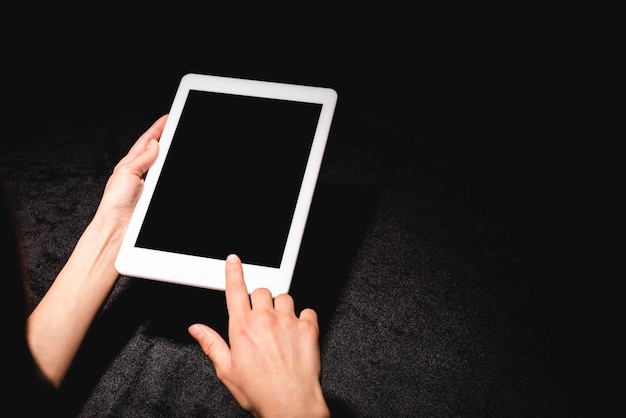 Foto vista tagliata di una donna in possesso di un tablet digitale con schermo vuoto su un panno di velluto nero