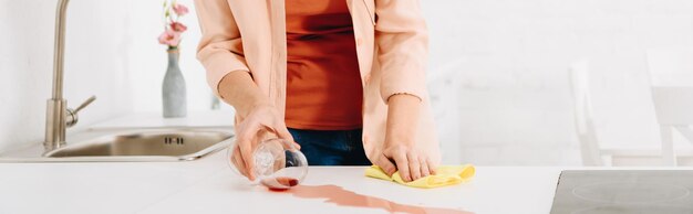 Foto vista ritagliata della donna che tiene il bicchiere di vino e pulisce la macchia