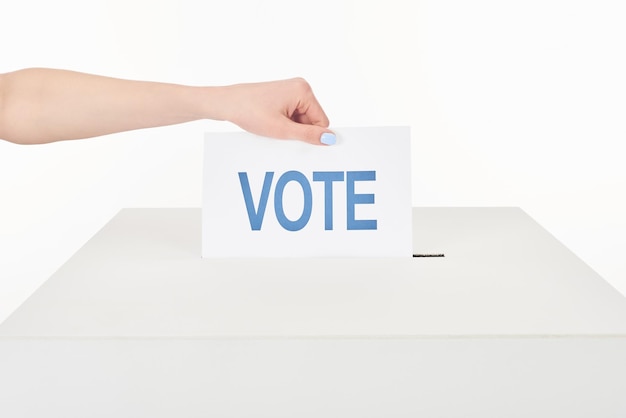 Cropped view of woman putting vote in box isolated on white