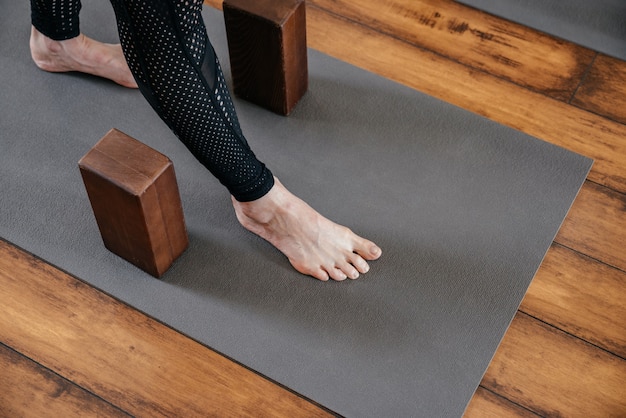 Cropped view of woman stretching her legs in yoga studio with yoga blocks