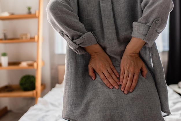 Cropped view of woman suffering from back pain at home