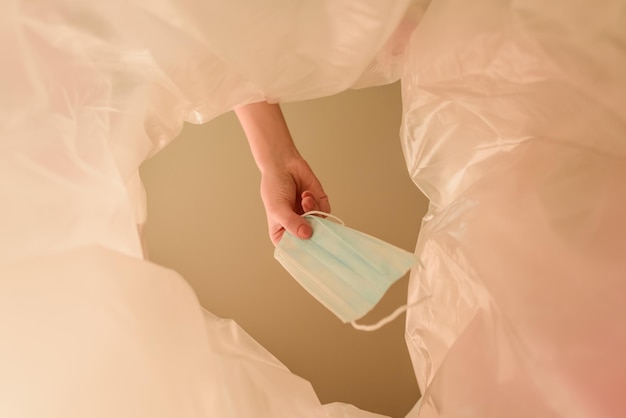 Cropped view of woman throwing medical mask in trash can end of quarantine concept