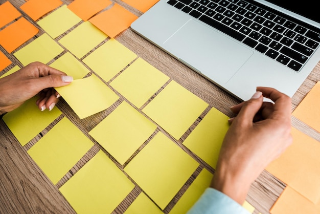 Photo cropped view of woman touching sticky note near laptop on desk