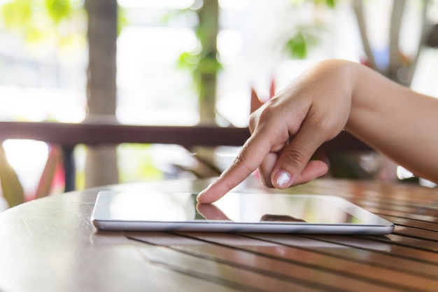 Cropped view of women using a digital tablet at outdoor coffee shop