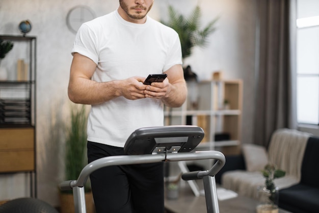 Cropped view of young sports man using phone looking online fitness class