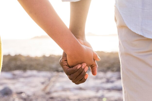 Cropped woman holding hands of man at beach