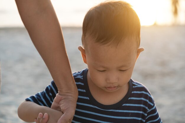 Foto donna tagliata che tiene in braccio il figlio in piedi sulla spiaggia