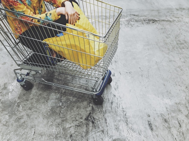 Foto donna tagliata seduta nel carrello della spesa