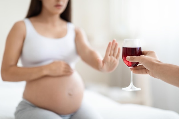 Cropped of young pregnant woman refuses to drink wine