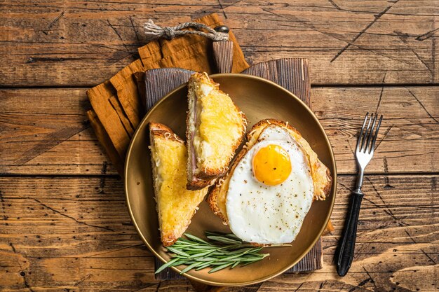 Croque monsieur en croque madame sandwiches met gesneden ham gesmolten emmentaler kaas en ei Franse toast Houten achtergrond Top uitzicht