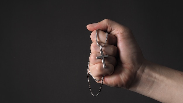 Cross or crucifix pendant and necklace in man hand.