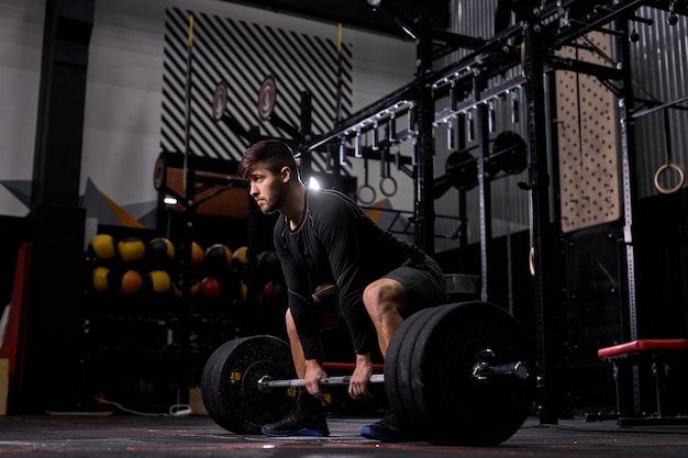 cross fit athlete lifting barbell at gym. Man practicing functional training powerlifting workout exercises alone, in sportswear. weightlifting, bodybuilding concept