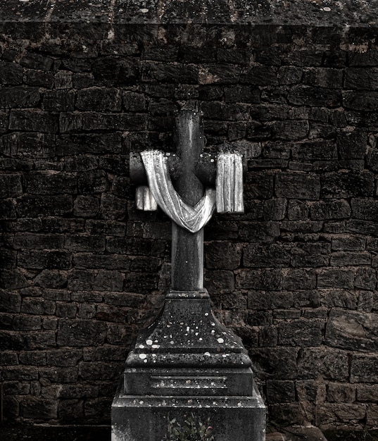 Cross in front of a wall with a white cloth on it at a cemetery
