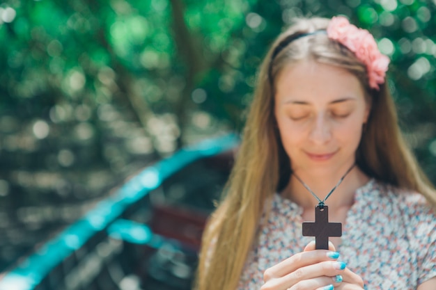 Foto croce nelle mani di una ragazza di close-up, ritratto di una donna sfocata