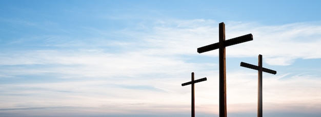 Cross of Jesus Christ empty over dramatic sunrise sky panorama with clouds.