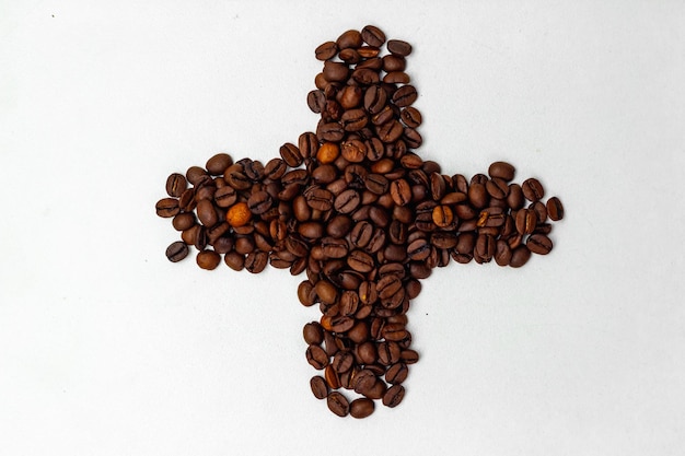 cross made of coffee beans on a white background