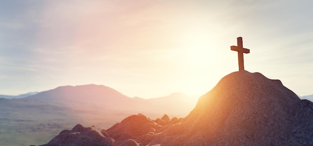 Cross on mountain peak at sunset christian religion