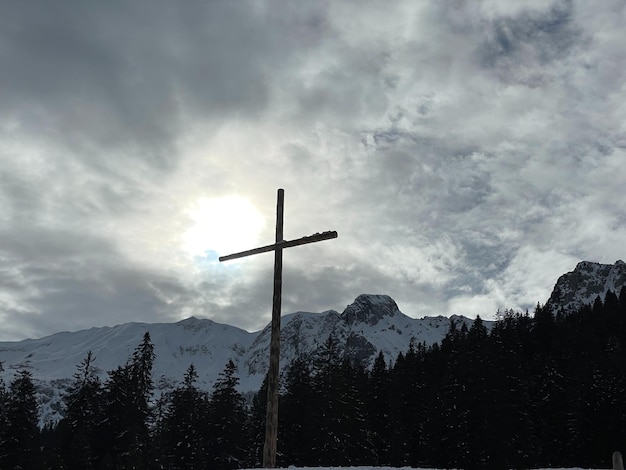 a cross on top of a hill beautiful clouds and sun view in mountains