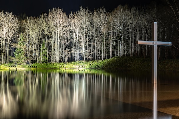 Foto croce sull'acqua con un riflesso invertito illuminato e illuminato la notte