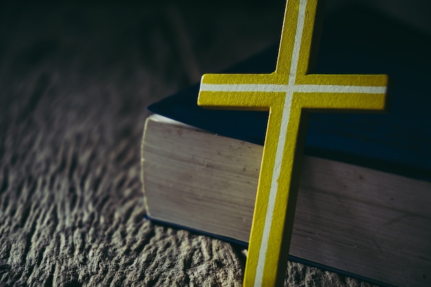 Cross with holy bible on wooden background.