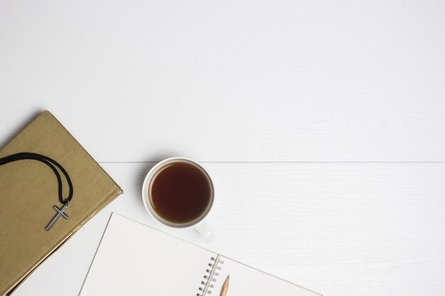 Photo a cross with notebooks with coffee on a white background