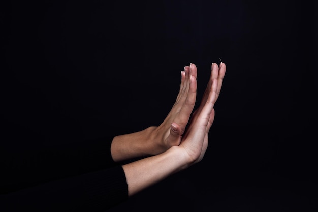 Crossed hands of person on black background showing stop sign Domestic physical psychological abuse relative aggression and gaslighting Copy space