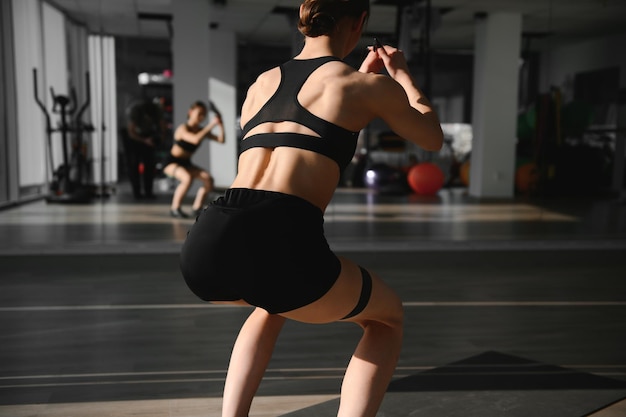 Concetto di stile di vita sano crossfit bello chaming adorabile bella signora modello di forma fisica muscolare sportiva che indossa mutandine sportive e top con fascia elastica nera sui muscoli delle gambe facendo addominali