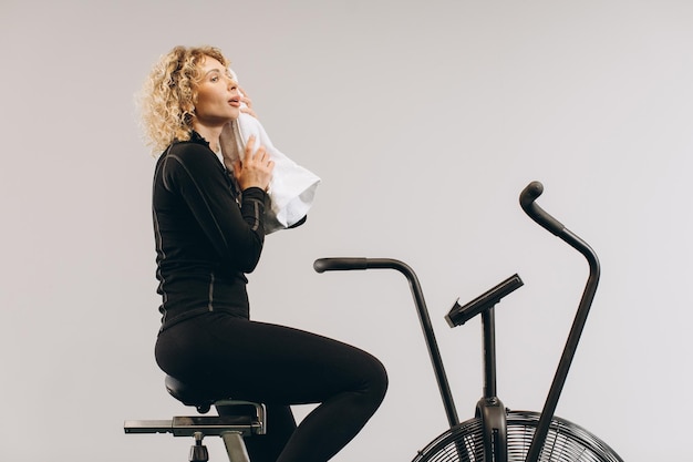 Crossfit vrouw doet intensieve cardiotraining op hometrainer Vrouw afgeveegd met een handdoek