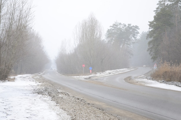 Foto incrocio su una strada asfaltata suburbana nell'orario invernale durante una bufera di neve