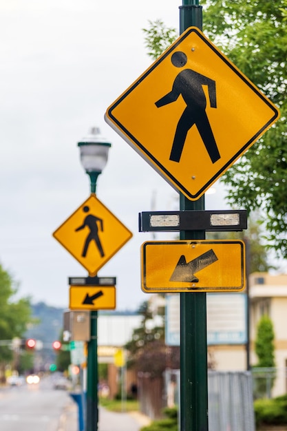 Crosswalk signs on a lamp post with arrows and a man symbol