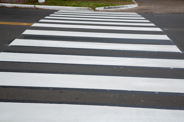 A crosswalk with white stripes and black stripes.