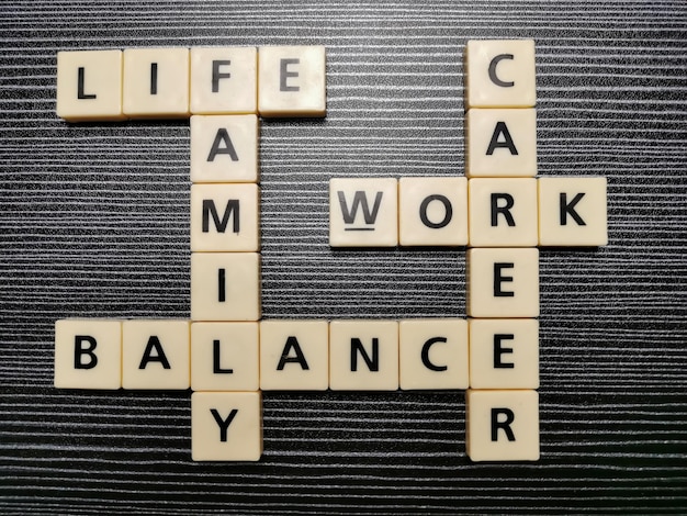 Crossword life family balance work career made from square letter tiles against black background.