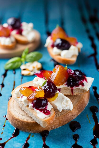 Crostini bruschetta met pruimenbessenmarmelade en geitenkaas op een blauwe turquoise blauwe achtergrond