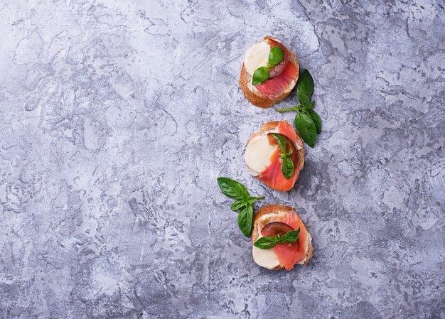 Crostini with salmon, mozarella, tomato and basil. Italian starter or appetizer