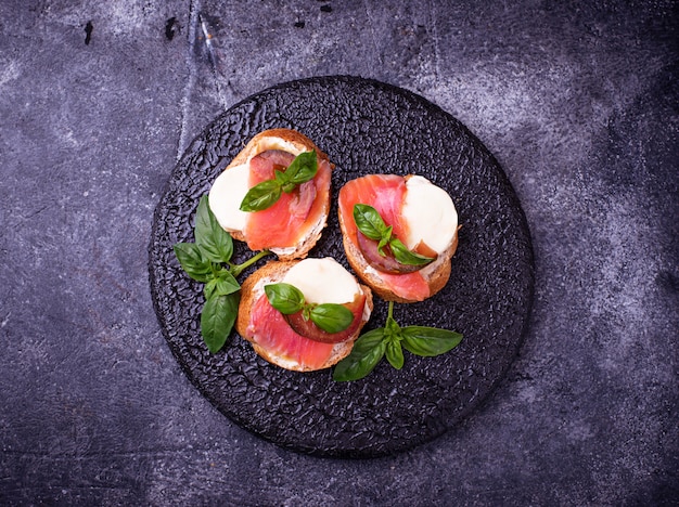 Crostini with salmon, mozarella, tomato and basil