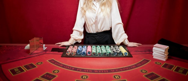 A croupier woman in a white shirt is standing at a red poker table Poker table in a luxury casino