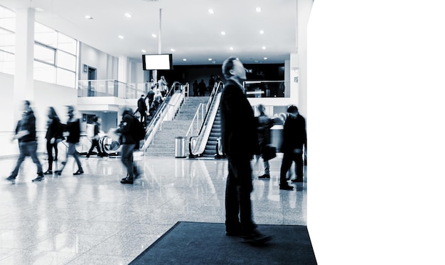 Crowd of anonymous blurred business people at a trade fair with\
banner and copy space for individual text