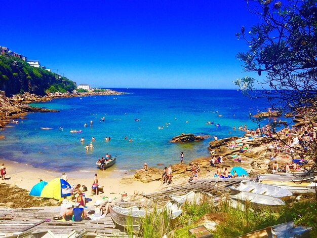 Crowd on beach against clear blue sky during sunny day