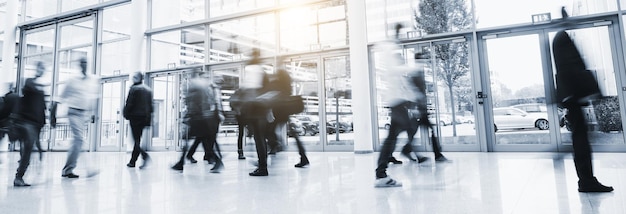 Crowd blurred business people walking in at a trade show floor,\
banner size. ideal for websites and magazines layouts