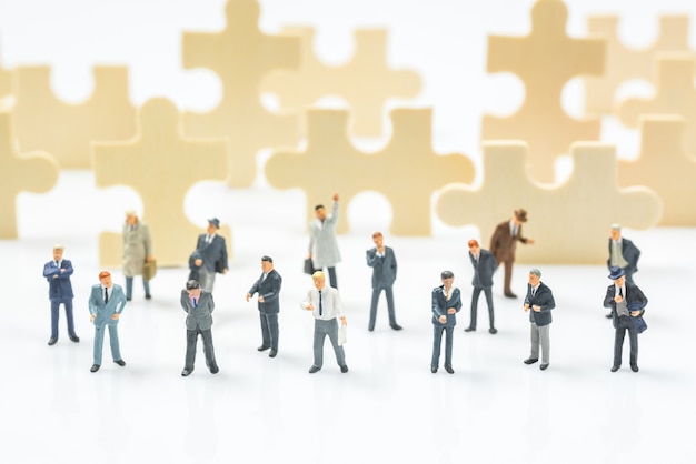 crowd of business miniature people on  jigsaw puzzle piece field background