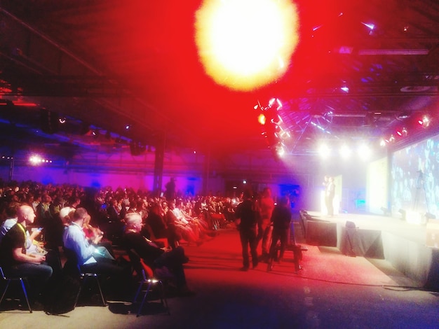 Photo crowd looking at illuminated stage in event