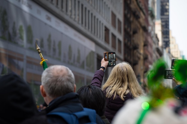 照片一大群人聚集在街头,其中一个穿着绿色的头发,手里拿着一个手机。